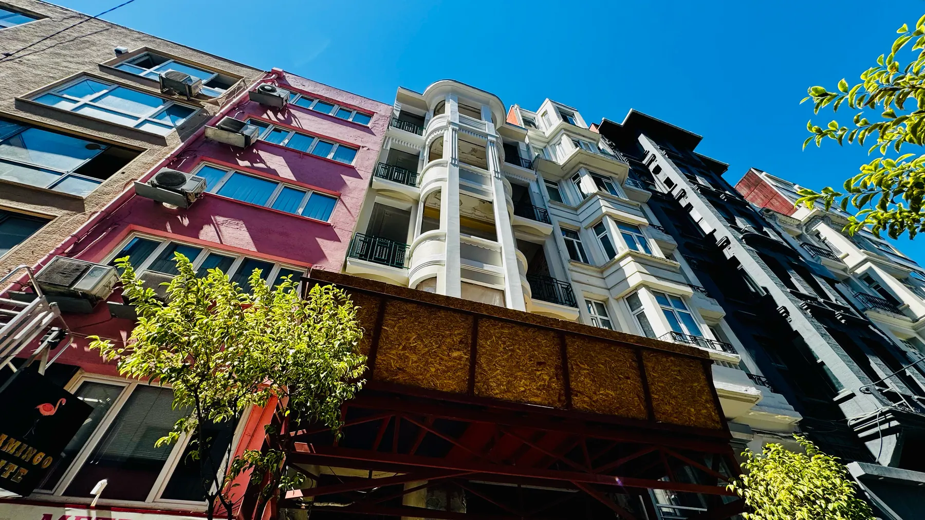 Apartmanın iki yanındaki yapılarla birlikte görünüşü: farklı dönemlerden cepheler yan yana