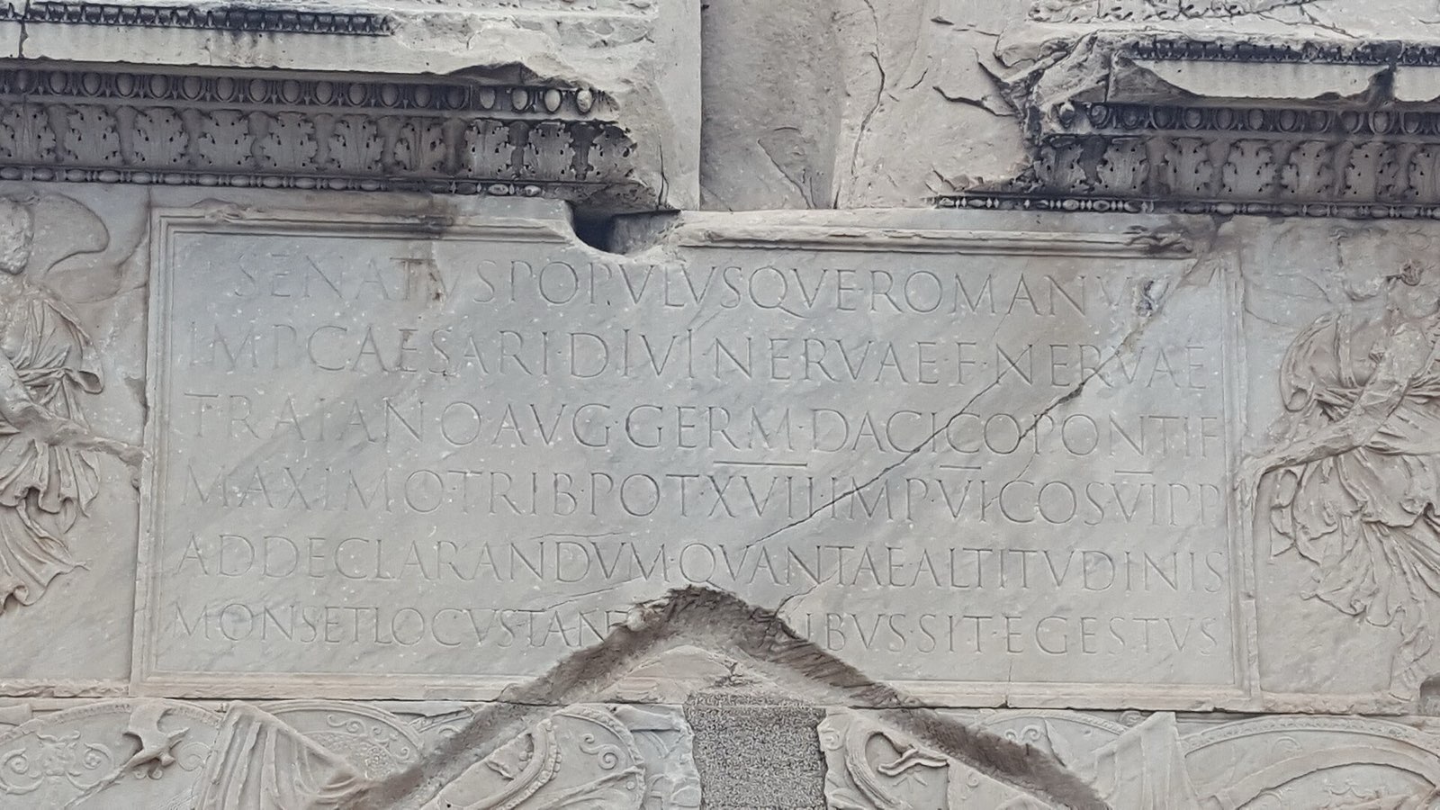Trajan sütununun kaidesindeki altı satırlık Latince kitabe: çerçeveli bir pano içinde, taşa oyulmuş harfler