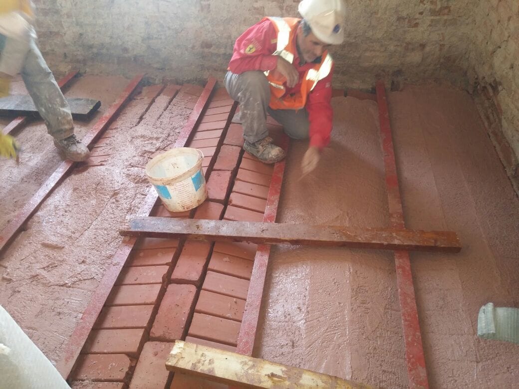 Usta diz üstünde, harç kovasıyla putrel arasındaki tuğlayı kavis verecek biçimde yerleştiriyor